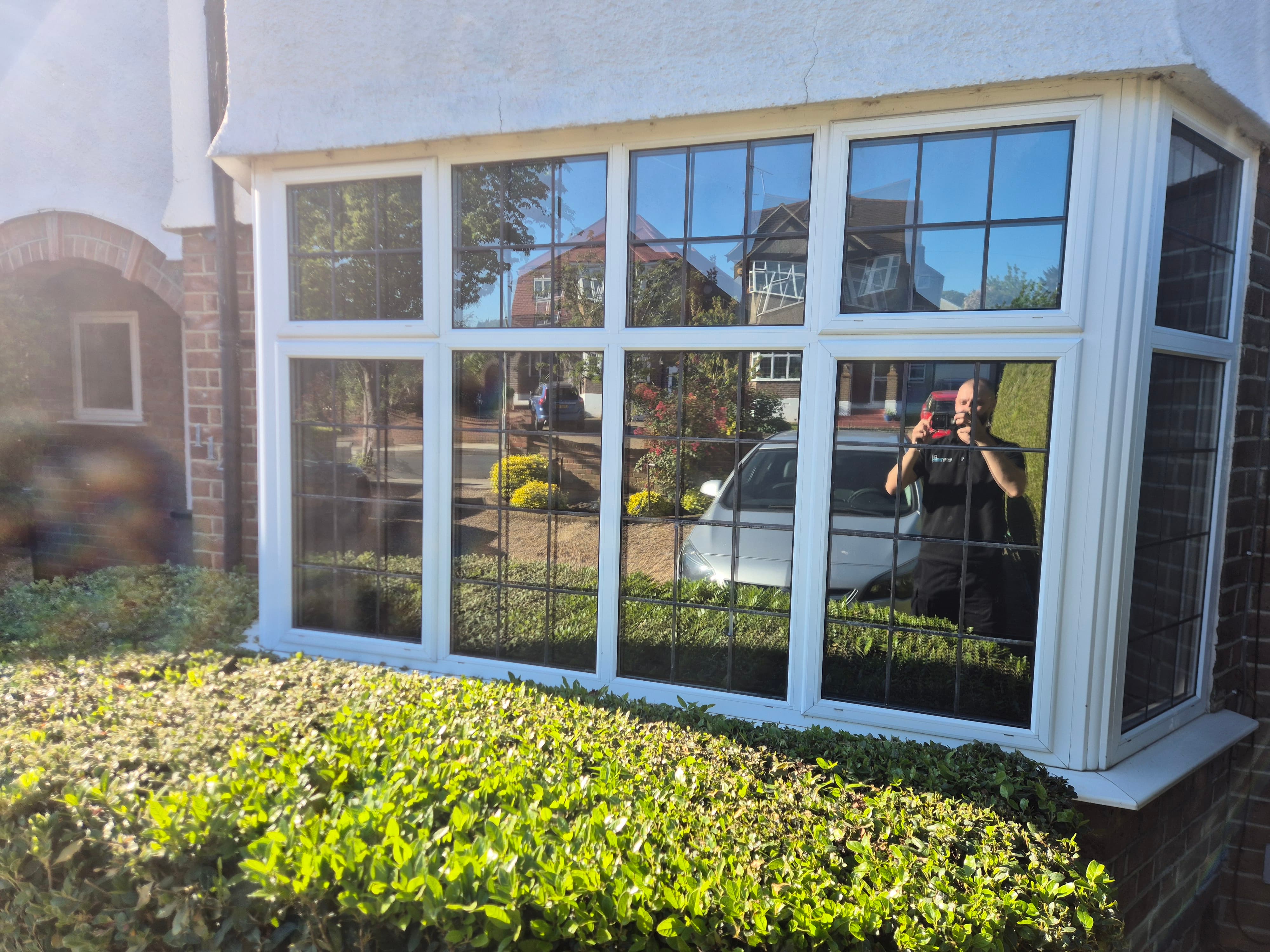 Exterior view of the same High Wycombe bay window after BucksTinting installation, showing a flawless mirror-effect reflecting the street and sky